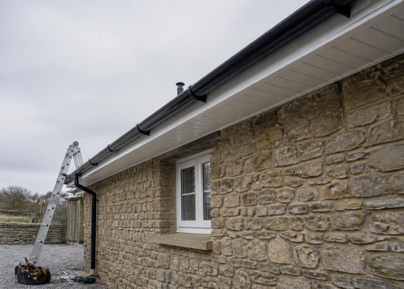 New fascia, soffit and guttering fitted to the roofline of a stone house