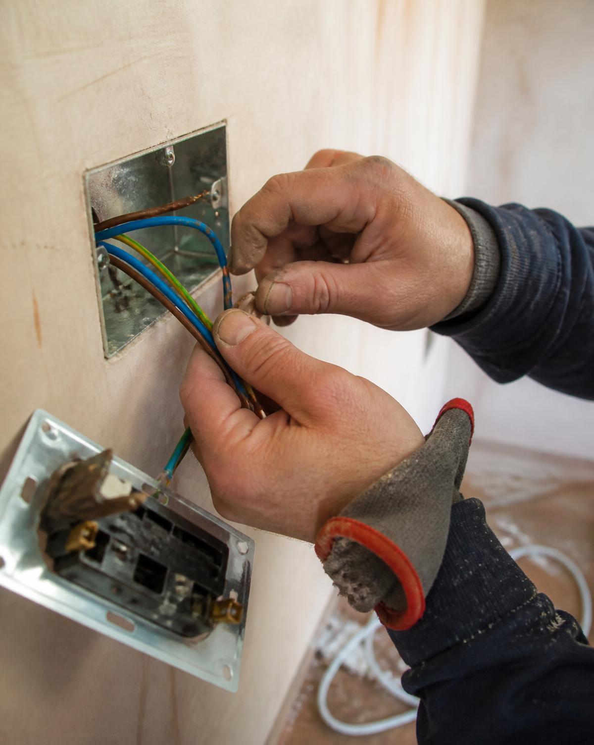 Electrician terminating copper wiring into a socket back box