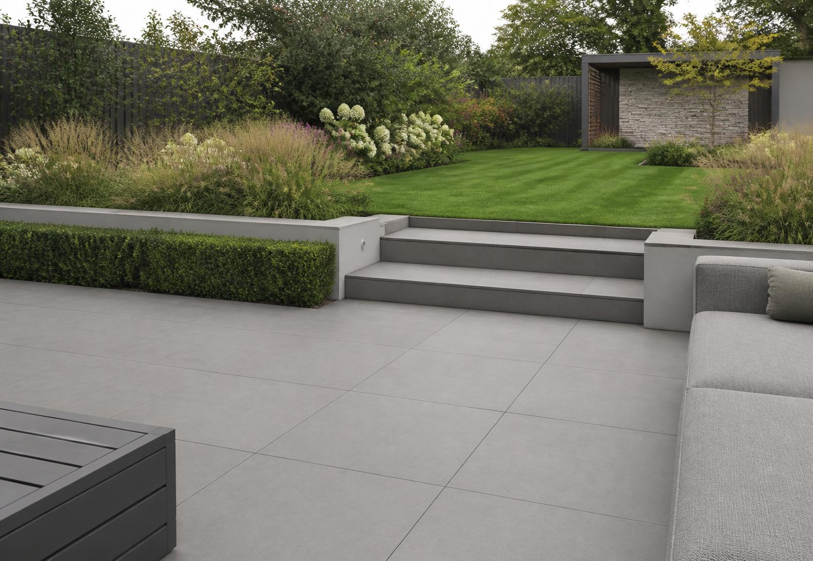 Contemporary porcelain paved terrace stepping up to a lawn
